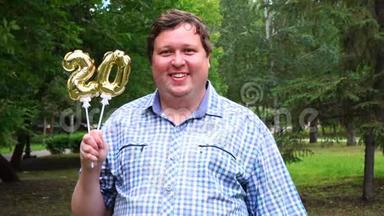 大个子拿着金色气球，在户外做20个数字。 20<strong>周年庆</strong>祝晚会